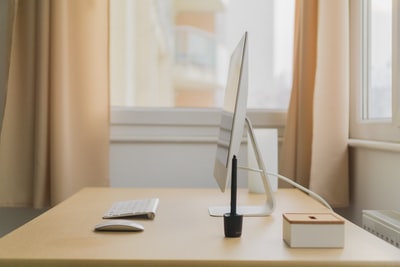 靠近窗户的木桌上放着苹果iMac